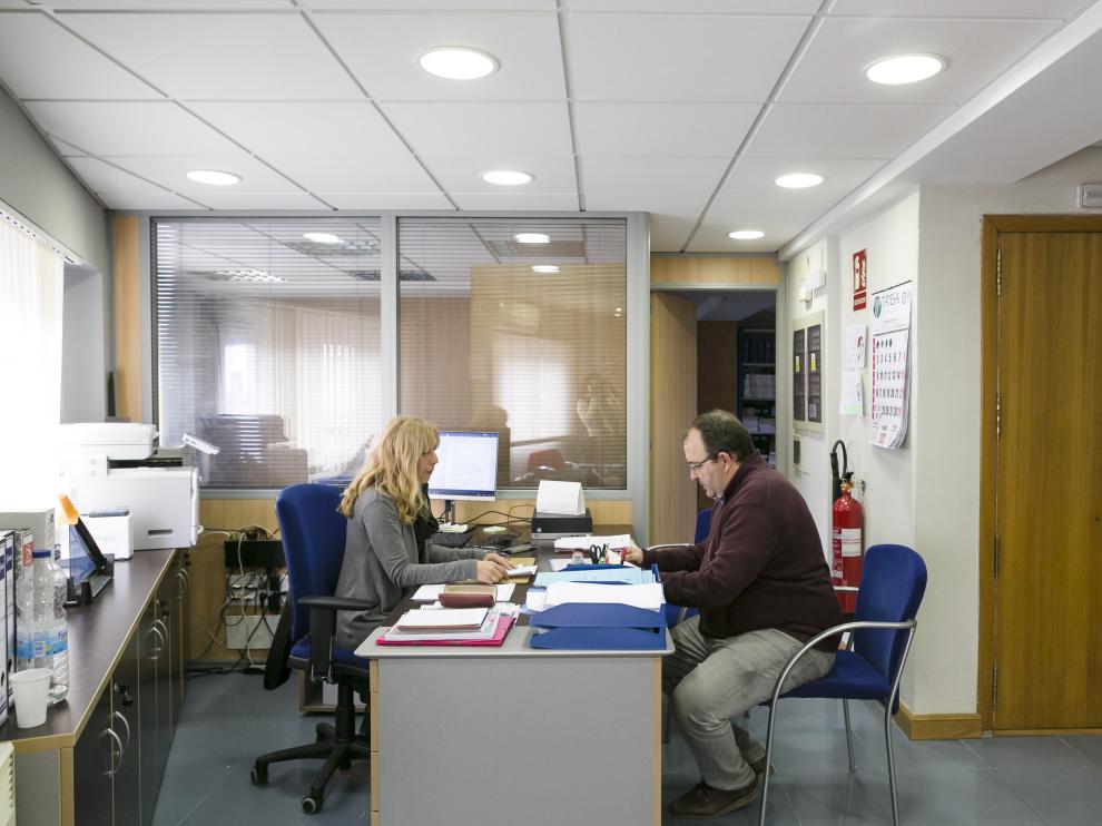 El presidente comarcal y una administrativa, en el interior de la sede en un piso de Utebo.