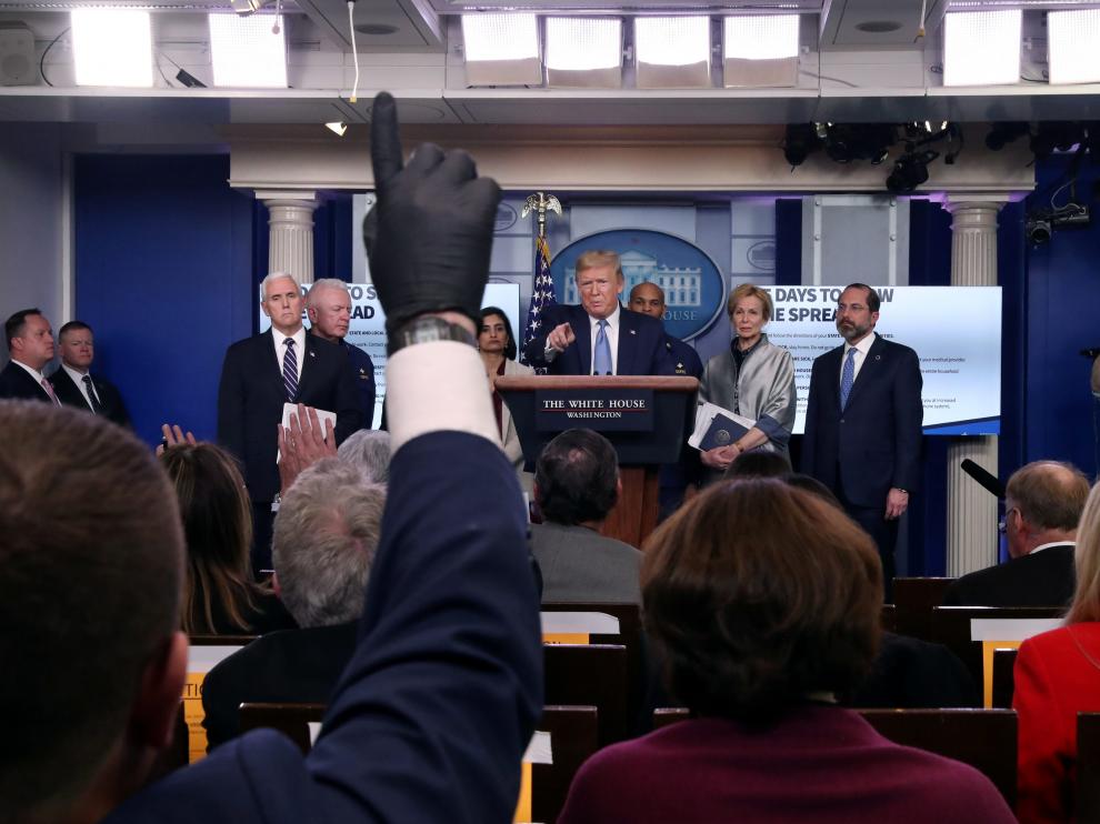 A reporter wears a latex glove while trying to ask a question of U.S. President Donald Trump during a news briefing on the coronavirus (COVID-19) at the White House in Washington