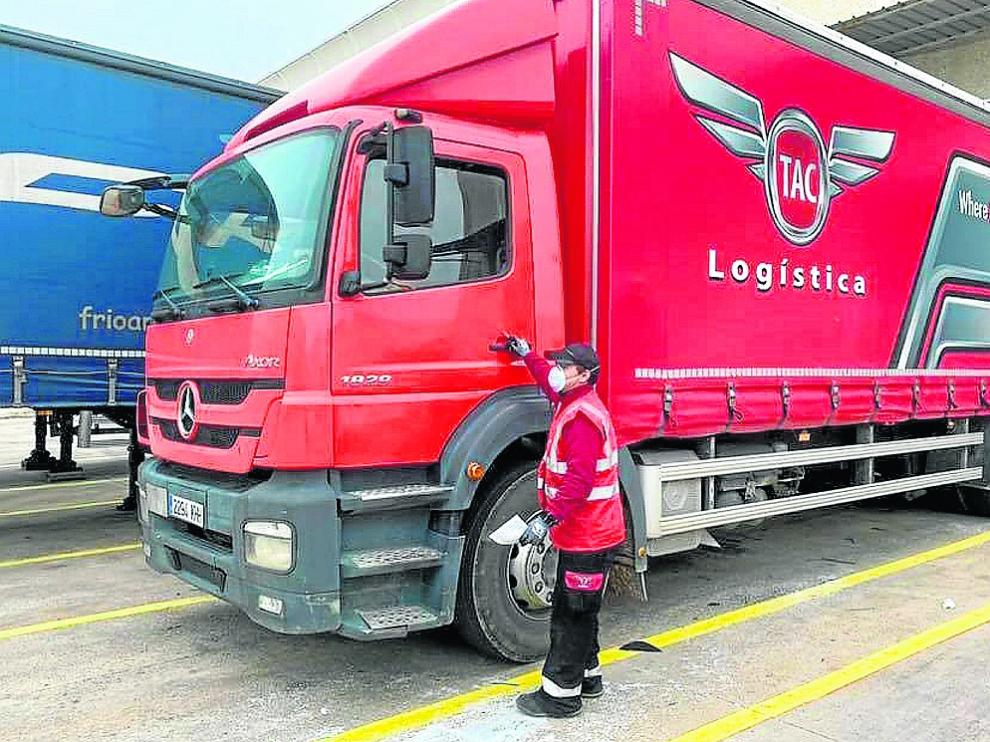 Un trabajador de la empresa zaragozana TAC Logística, junto a un camión de la firma.