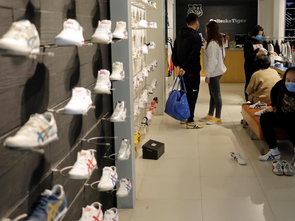 Personas con máscaras faciales compran este viernes en una zapatería de un centro comercial en Pekín.