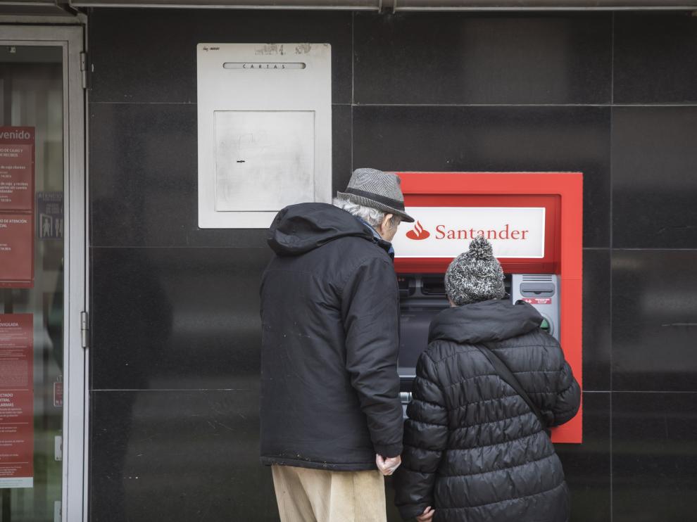 Dos clientes en un cajero de una oficina bancaria en Zaragoza.