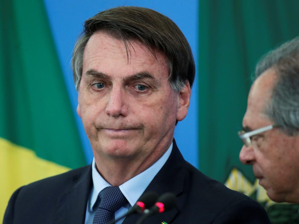 Brazil's President Jair Bolsonaro reacts near Brazil's Economy Minister Paulo Guedes during a media statement announcing economic measures, amid coronavirus disease (COVID-19) outbreak, in Brasilia