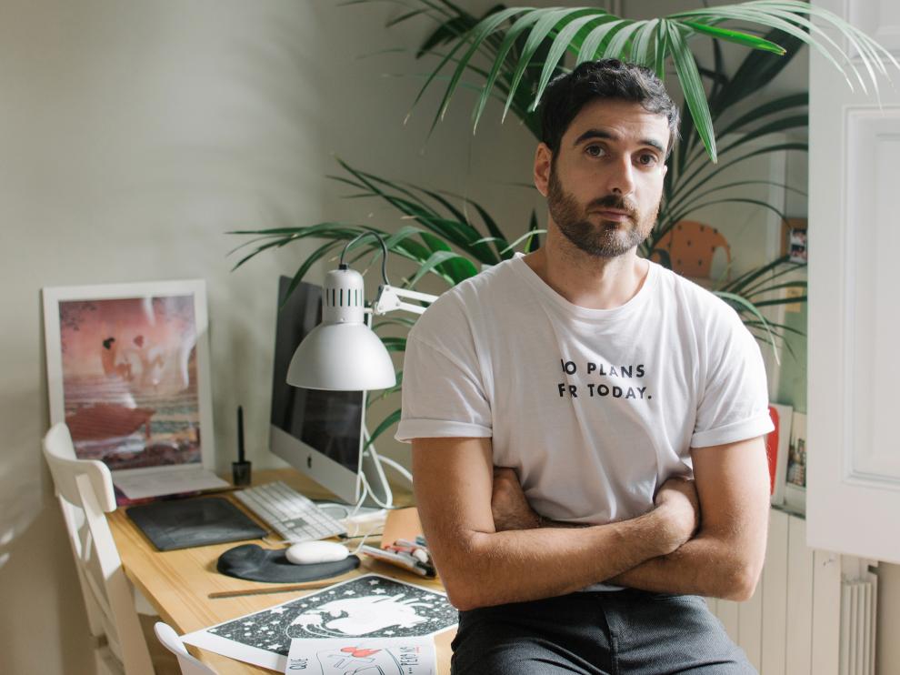 Alfonso Casas con algunas de sus ilustraciones sobre la mesa.