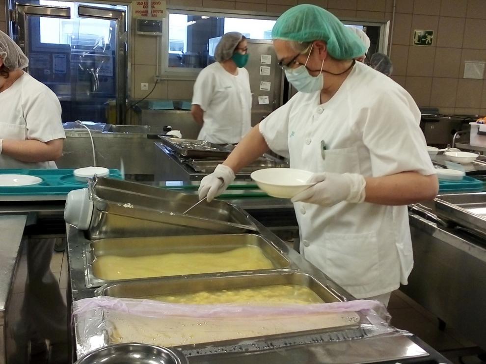Una de las trabajadoras de la cocina del Servet sirve una ración en un plato.