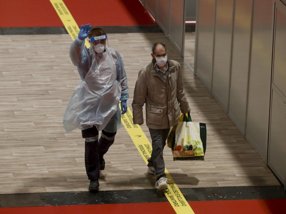 Un paciente es acompañado por un voluntario del hospital de Ifema tras recibir el alta este sábado.