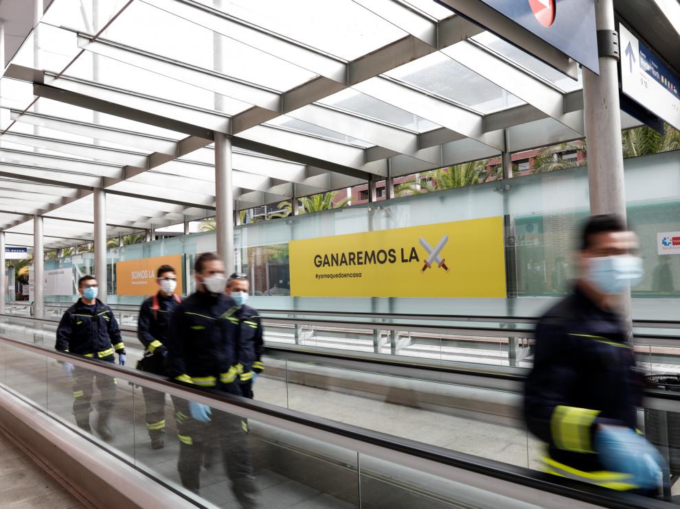 Bomberos de la Comunidad de Madrid protegidos con mascarilla caminan por las inmediaciones del hospital de campaña montado en Ifema, el sábado en Madrid.