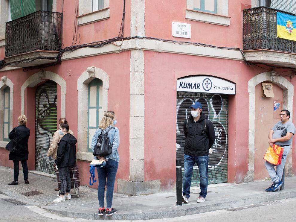 Vecinos en una fila para entrar en una tienda en el barrio de la Barceloneta.