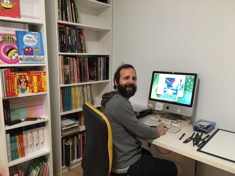 El ilustrador Artur Laperla, en su mesa de trabajo, junto a parte de su biblioteca.