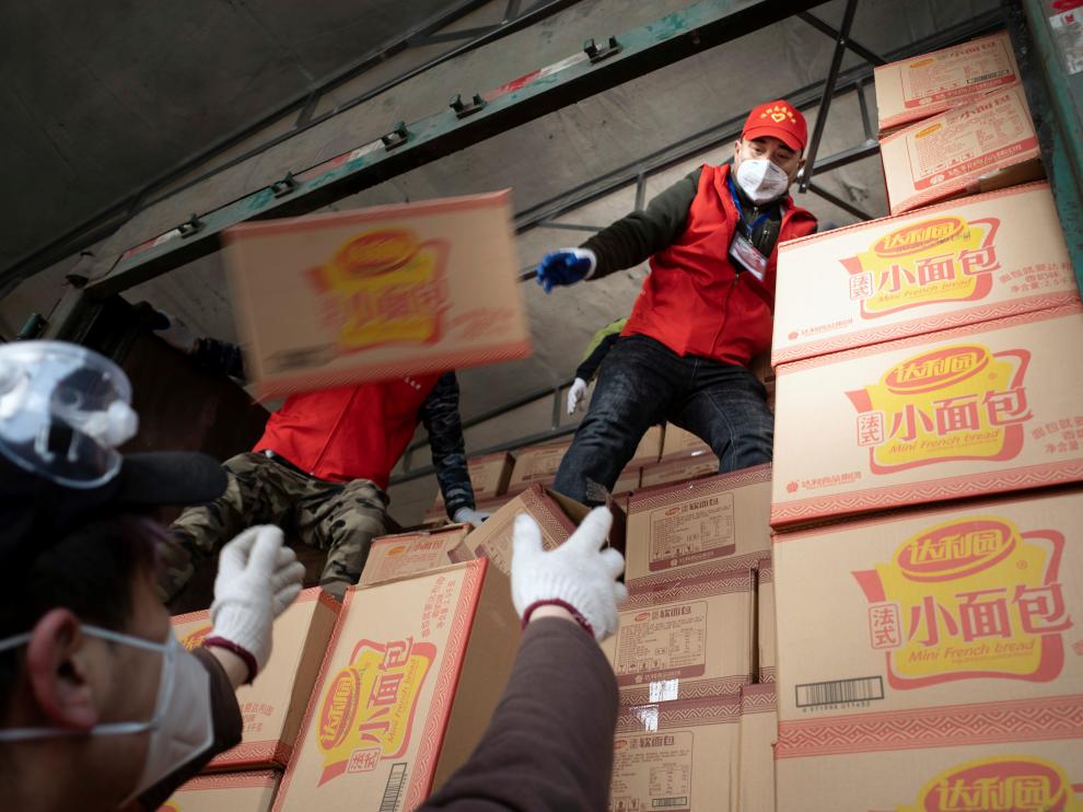 Voluntarios cargan cajas de mascarillas en Xiaogan, en la provincia de Hubei