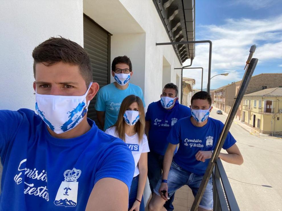 Miembros de la Comisión de Fiestas junto al cohete anunciador y luciendo las mascarillas personalizadas que ha realizado y entregado el Ayuntamiento de Tardienta.