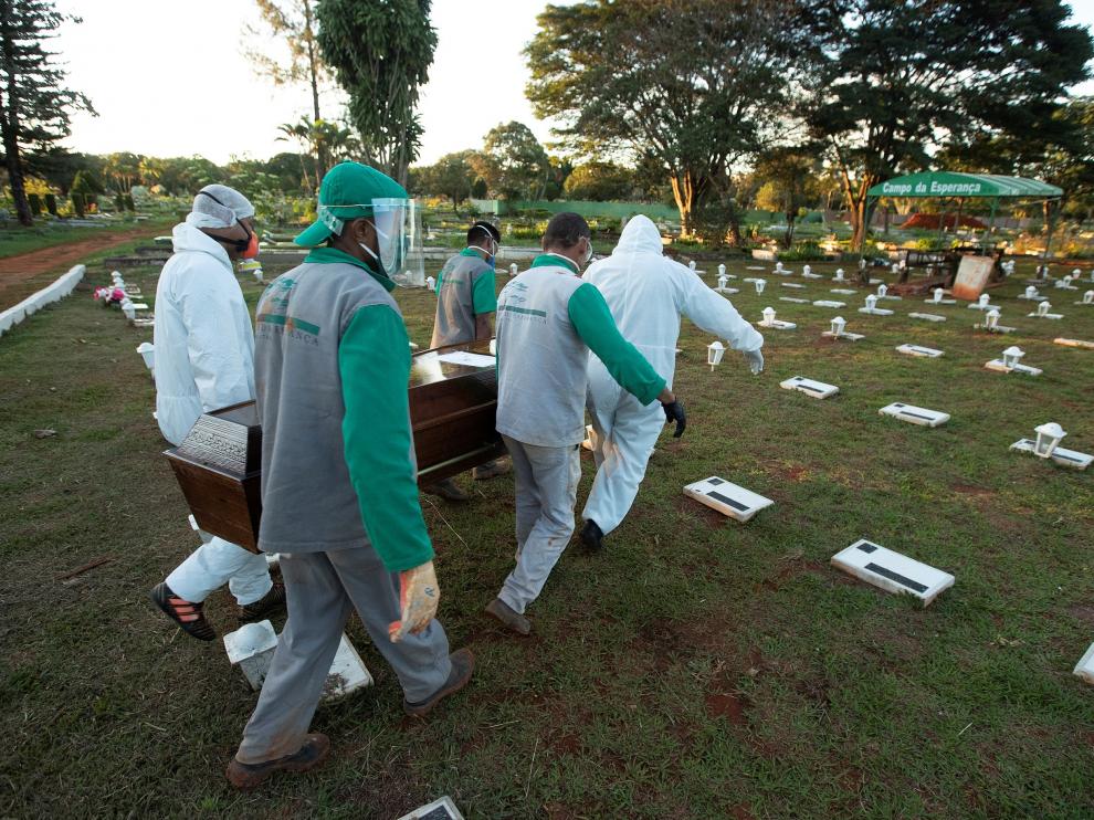 Trabajadores del cementerio Campo de Esperanza entierran una víctima de la pandemia este jueves, en Brasilia (Brasil).