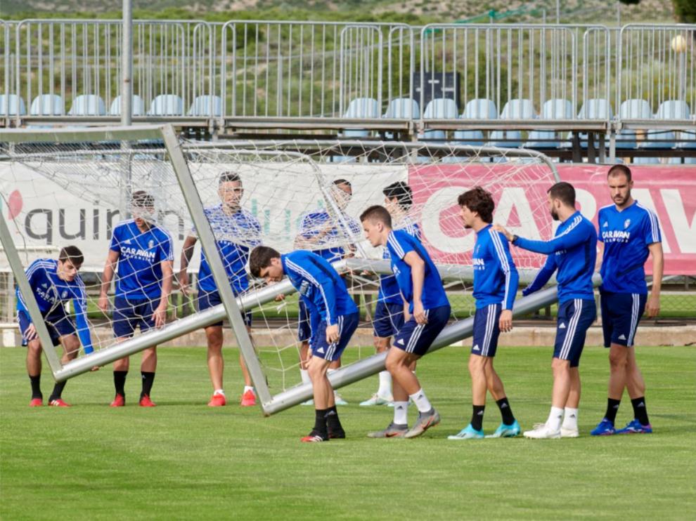 Uno de los grupos de trabajo del Real Zaragoza, traslada una portería portátil en la Ciudad Deportiva durante una sesión de entrenamiento.