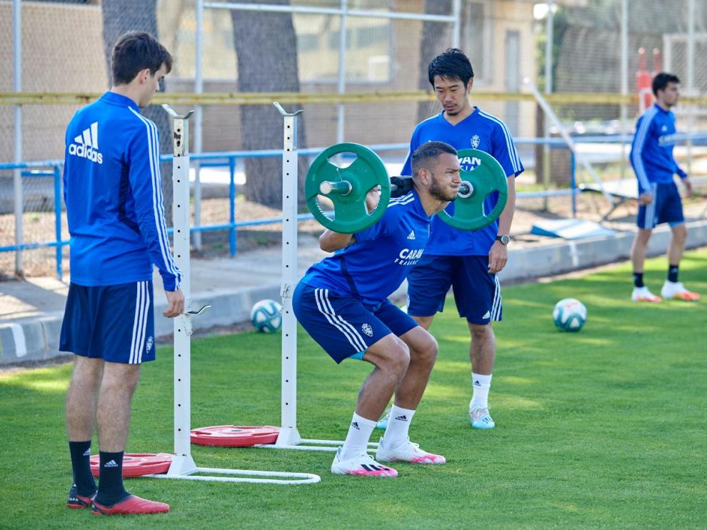 Luis Suárez levanta pesas, ante la mirada de Kagawa y el joven Francho.