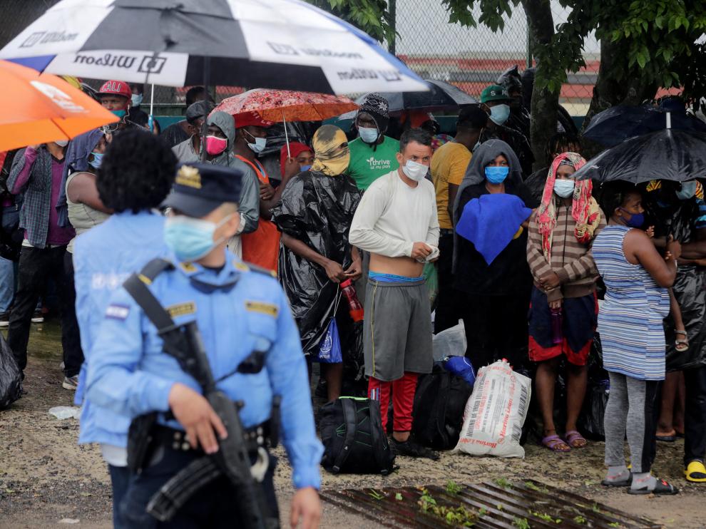 Stranded migrants from Africa, Cuba and Haiti shield from the rain in Tegucigalpa