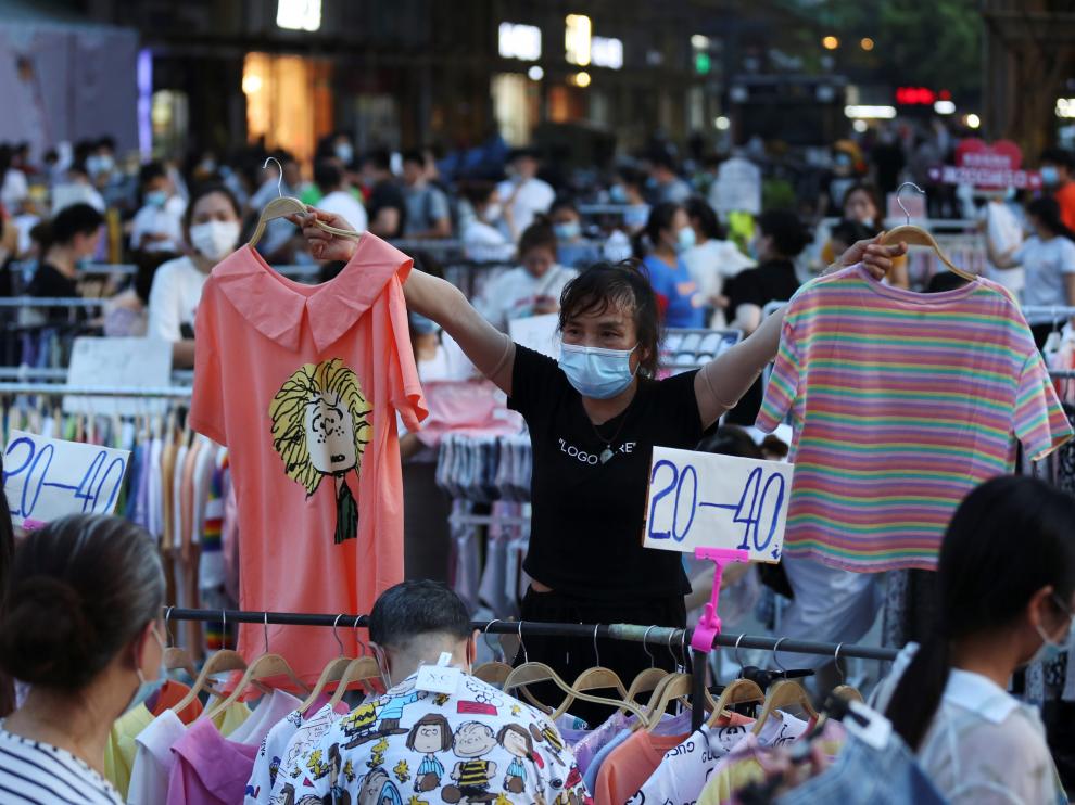 Vendor holds clothing items for sale at a street stall on Jianghan Road in Wuhan