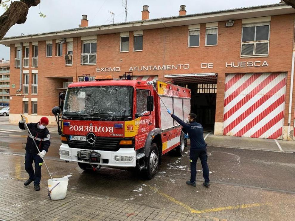 Bomberos de Huesca limpiando uno de los camiones a las puertas del parque.