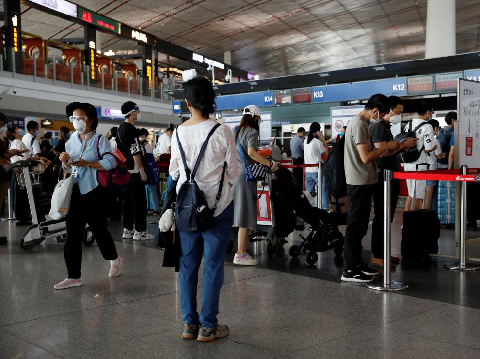 People wearing protective gear line up at Beijing Capital International Airport