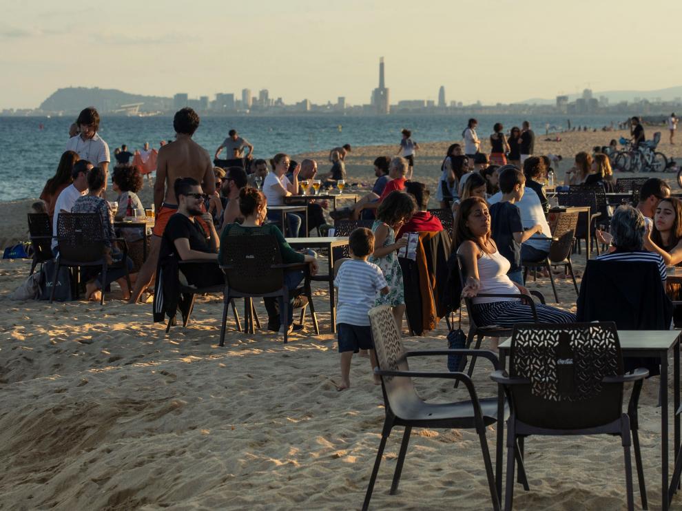 Varias personas tomando algo en la playa de Barcelona