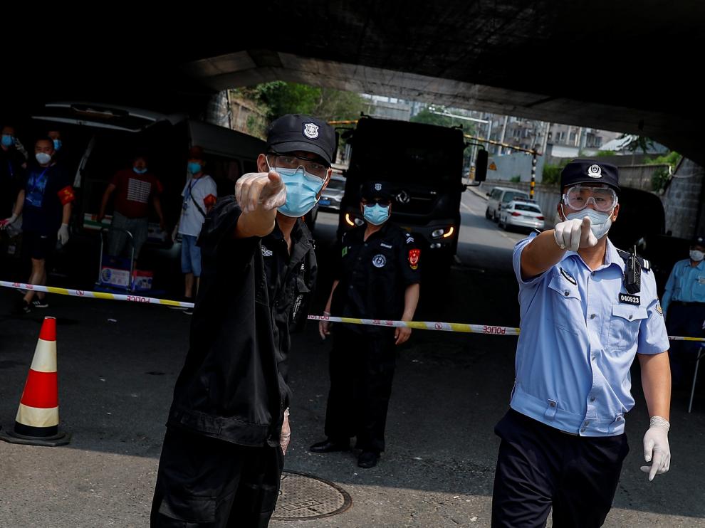 Police and security personnel attempt to prevent the photographer from taking pictures at the barrier near the Xinfadi market that has been placed under lockdown after a new outbreak of the coronavirus disease (COVID-19) in Beijing