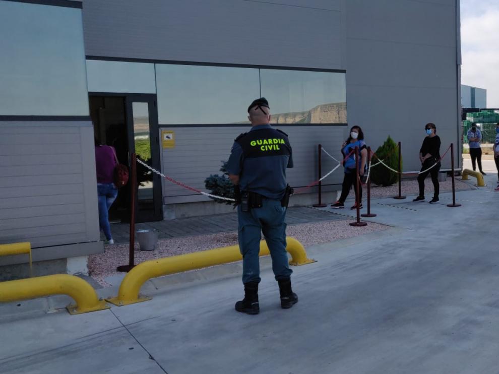 Los trabajadores guardan cola manteniendo la distancia de seguridad frente a las instalaciones de la empresa.