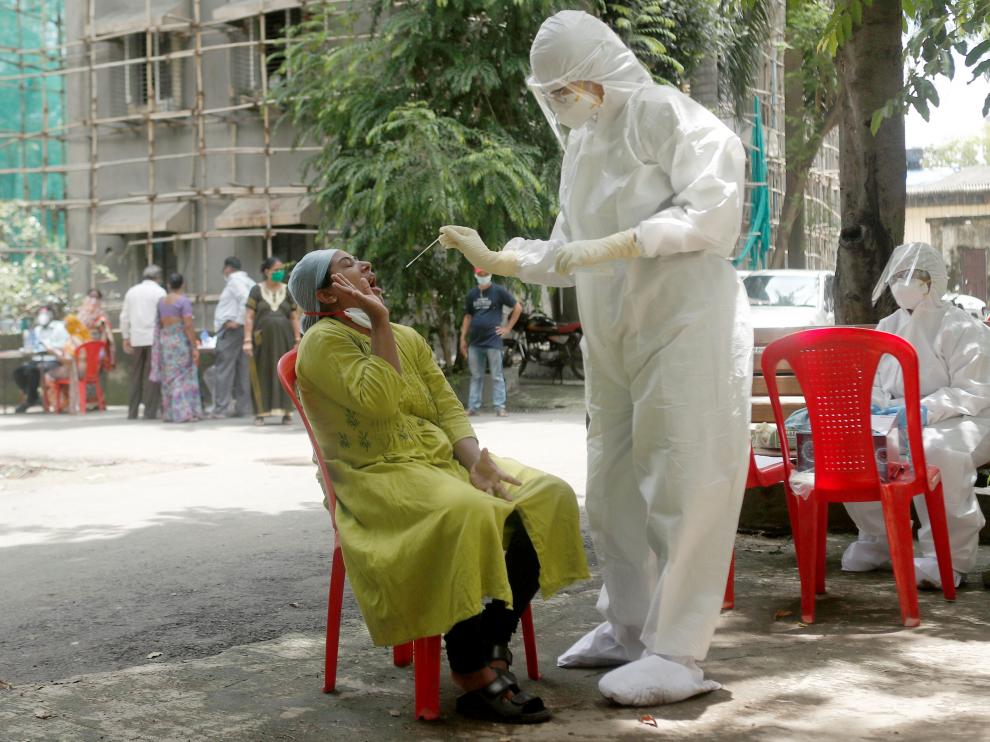 A health-worker wearing personal protective equipment (PPE) collects a sample using a swab from a woman during a check-up campaign for the coronavirus disease (COVID-19), at a residential society in Mumbai