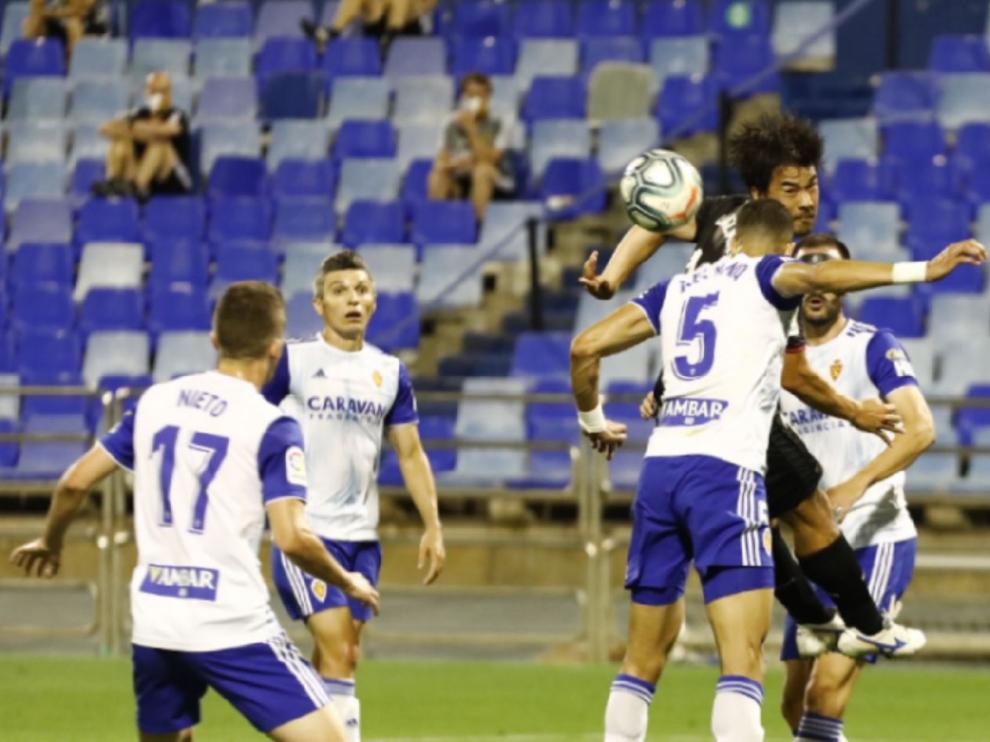 Una jugada defensiva del Real Zaragoza en un centro que intenta rematar el japonés del Huesca Okazaki.
