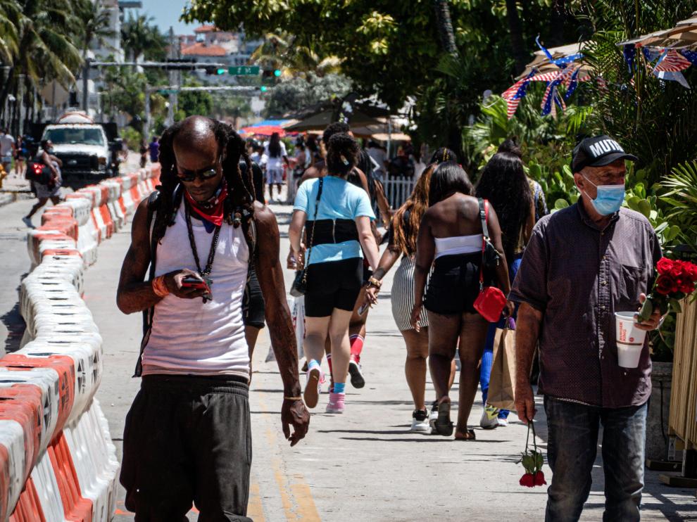 Personas con y sin mascarilla pasean por Miami Beach (Florida).