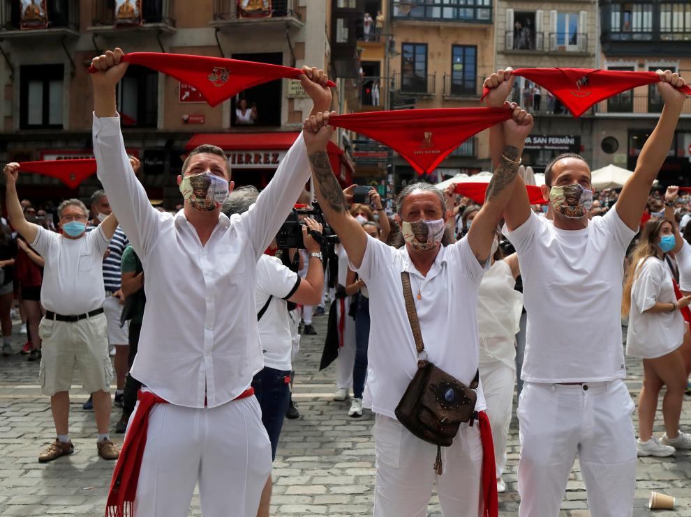 Revellers hold up traditional red scarves in front of the town hall where the firing of "chupinazo", which opens the San Fermin festival that was cancelled due to the coronavirus disease (COVID-19) outbreak, should have taken place, in Pamplona, Spain July 6, 2020. REUTERS/Jon Nazca [[[REUTERS VOCENTO]]] HEALTH-CORONAVIRUS/SPAIN-BULLS