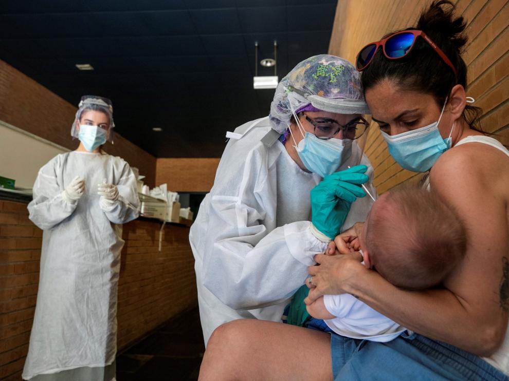 Una sanitaria realiza un test PCR a un niño en un espacio habilitado en un centro de salud de Zaragoza.