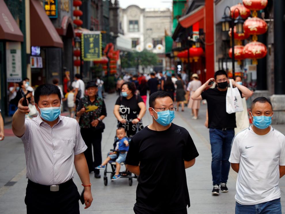 People wearing face masks following the coronavirus disease (COVID-19) outbreak, walk past a giant screen showing a news footage of Chinese President Xi Jinping wearing a face mask, at a shopping area in Beijing, China July 31, 2020. REUTERS/Tingshu Wang [[[REUTERS VOCENTO]]] SPACE-EXPLORATION/CHINA-XI