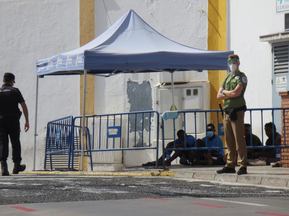Un policía y un guardia de seguridad vigilan a un grupo de inmigrantes que han logrado saltar la valla en Melilla.