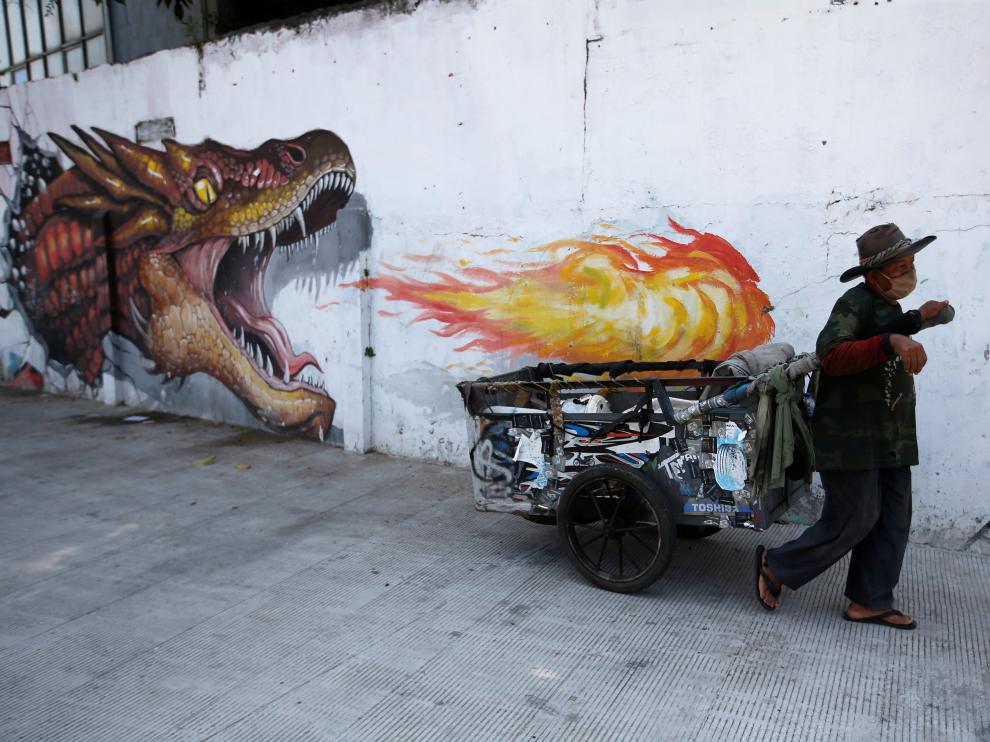 Un hombre se protege con mascarilla ante un mural sobre el coronavirus en Jakarta