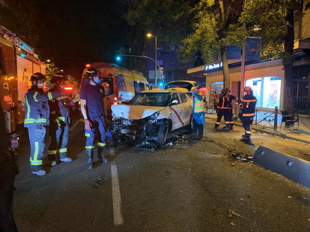 Los Bomberos retiran el vehículo, encajado en una aleta de tiburón, y sanean la zona afectada, en Madrid.