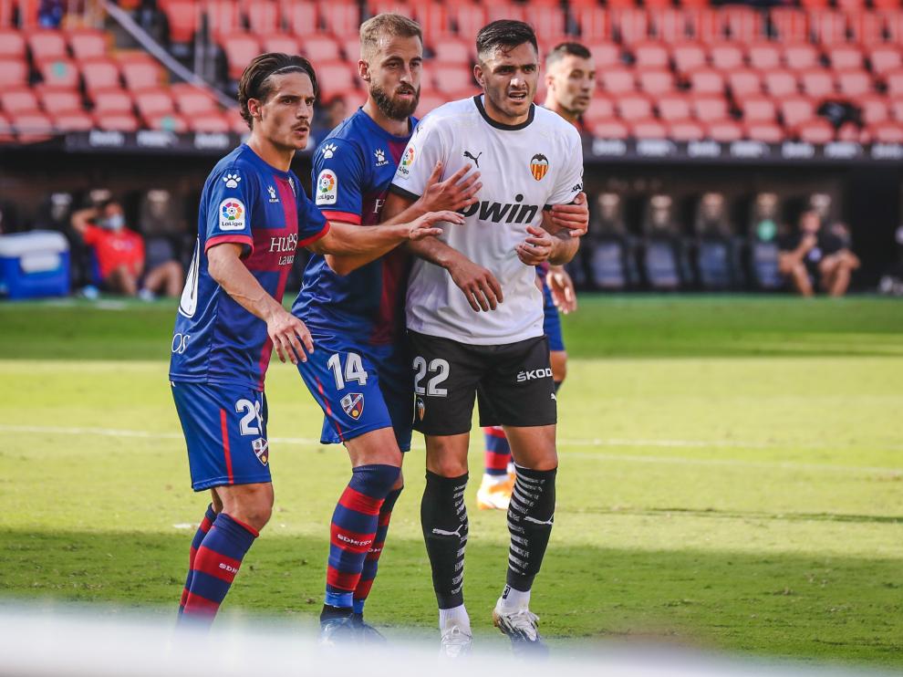 Seoane y Pulido, de la SD Huesca, junto a Maxi Gómez, del Valencia.