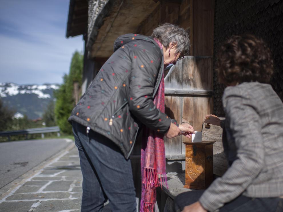 Una ciudadana introduce su voto en una urna portátil en una localidad suiza.