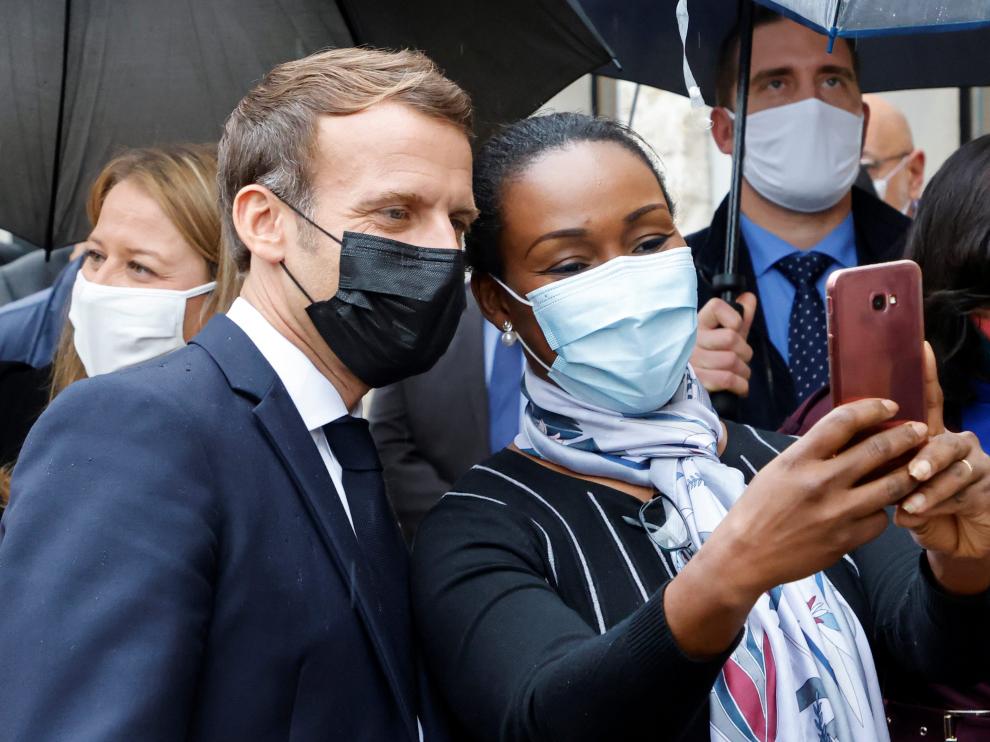 French President Emmanuel Macron poses for a selfie with a resident during a visit in Les Mureaux