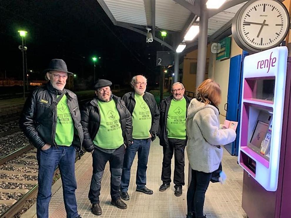 Una viajera compra su billete en la máquina instalada en el exterior de la estación de Monzón ante representantes de Cambiar Monzón.
