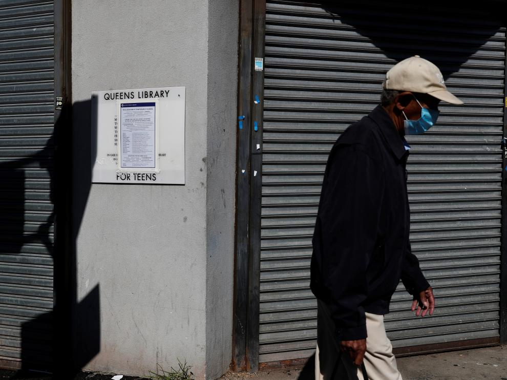 A man walks with a protective face mask past a closed library amid the coronavirus disease (COVID-19) outbreak in the Far Rockaway section of the Queens borough of New York