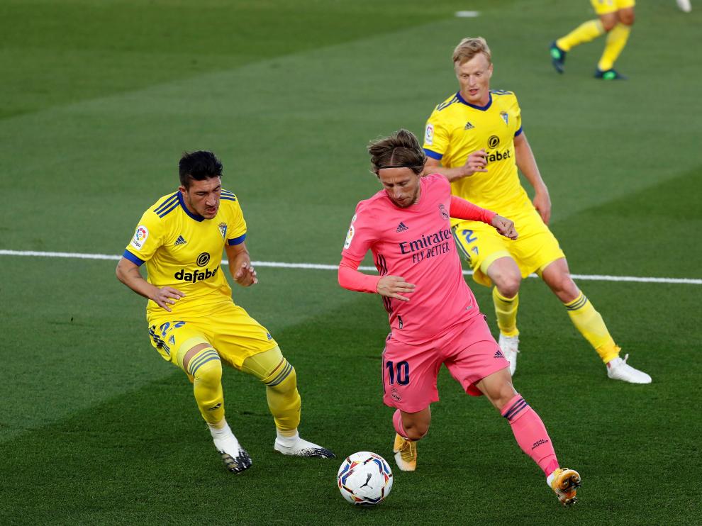El centrocampista del Real Madrid Luka Modric (c) juega un balón entre Luis Espino (i) y Jens Jonsson, ambos del Cádiz