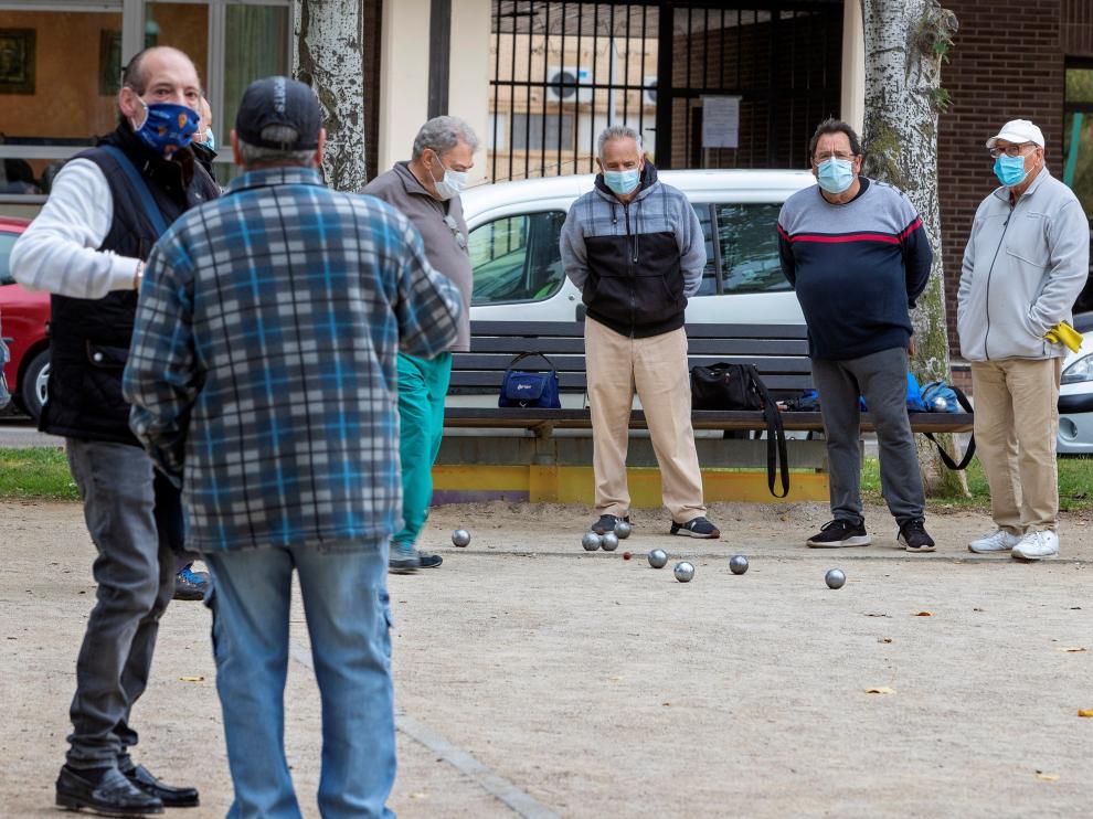 Varias personas juegan a la petanca en una calle de Zaragoza.