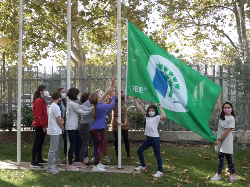 Los alumnos izan la bandera que les acredita como Eco Escuela