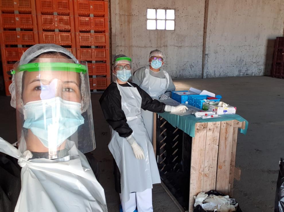 Dos rastreadoras y el coordinador médico del Centro de Salud de Fuentes de Ebro hacen PCR con los EPI en una finca de Pina, este verano.