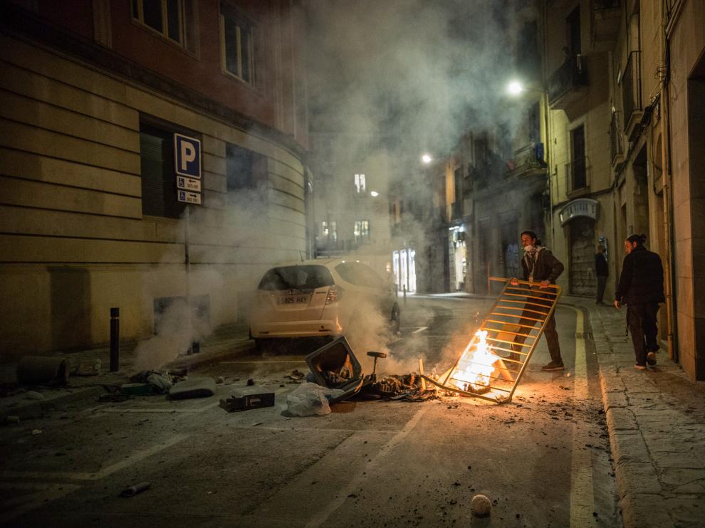Un joven coloca una barricada en una calle de Barcelona.