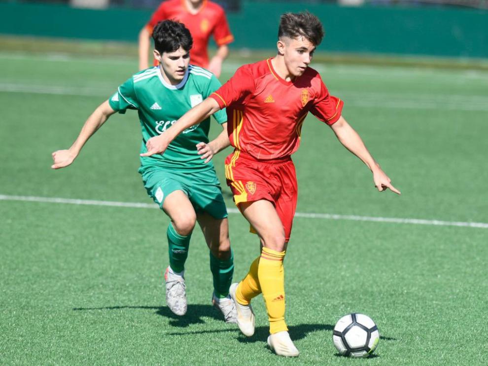 Un jugador zaragocista conduce el balón ante la presión de un jugador local.