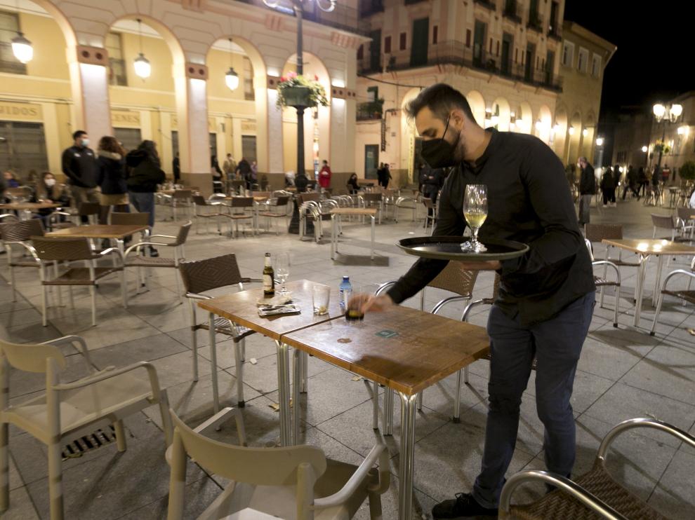 Un camarero limpia las últimas mesas para cerrar a las 20.00 en la plaza de López Allué de Huesca.