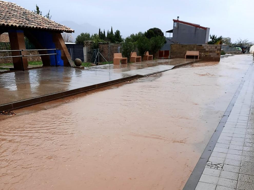 Agua acumulada en una calle de Apiés tras la lluvia de este sábado.