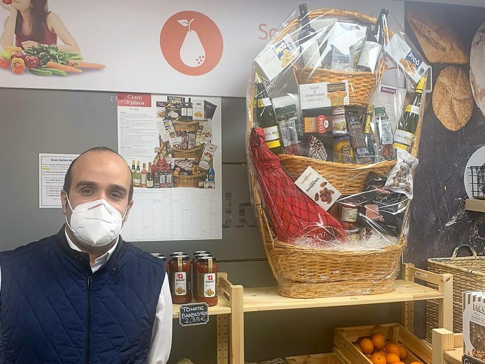 Carlos Paúles junto a la cesta de Navidad que se sortea, colocada en la tienda de El Temple.