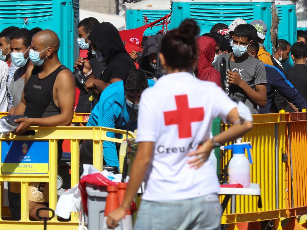 Una voluntaria de Cruz Roja mira a los inmigrantes en el puerto de Arguineguín