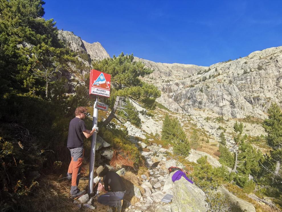 La nieve está prácticamente ausente de la alta montaña, salvo en cotas de 3.000 metros. En la imagen, los guardas del refugio de Bachimaña estos días, junto a un cartel de prevención de aludes.