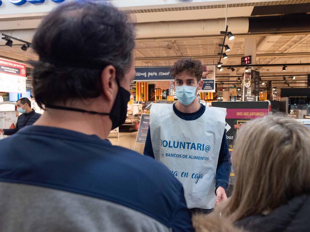 Un voluntario del Banco de Alimentos, este pasado viernes, explica a unos clientes cómo pueden hacer su donación al pasar por caja